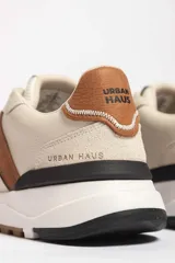 Zapatillas deportivas marrones con detalles en blanco y suela color caramelo.