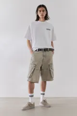 Remera blanca de algodón pesado con cuello redondo ribeteado, hombros caídos, bajo recto y estampado pequeño en el pecho. Corte oversized.