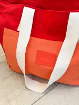 Bolso tipo tote, color rojo y naranja, con asas de algodón color blanco.