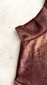 Body de terciopelo marrón con estampado de piel de serpiente, cuello alto, mangas largas con orificio para el pulgar y espalda descubierta.