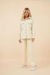 Camisa estilo leñador color beige con textura de espiga, de manga larga con puños abotonados, cuello clásico, cierre frontal con botones y dos bolsillos de parche con solapa abotonada en el pecho.