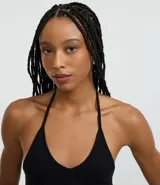 Top cropped de algodón color amarillo pálido, con escote en V pronunciado y tirantes finos que se atan en la nuca (estilo halter). El tejido es acanalado.