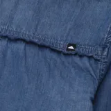 Camisa de denim azul de manga larga con cuello clásico, cierre frontal con botones y dos bolsillos con solapa en el pecho.