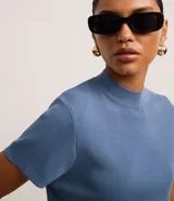Blusa de punto color celeste, con cuello alto, manga corta y malla texturizada.