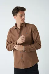 Camisa marrón de manga larga con bolsillo en el pecho y cierre con botones.