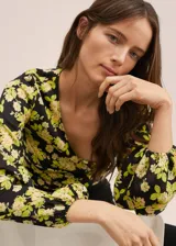 Blusa crop de tejido satinado con estampado floral, cuello cruzado, mangas largas con puños elásticos y elástico en el bajo.