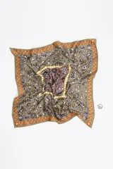 Pañuelo tipo twilly diseñado como charm para bolso, con estampado floral e ikat en tonos azul, verde, amarillo y naranja sobre fondo blanco. Incluye un anillo metálico plateado en forma de corazón que sujeta el pañuelo.