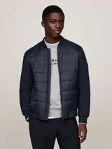 Campera bomber azul marino con mangas largas, cuello, puños y bajo acanalados. Presenta cierre frontal con cremallera, dos bolsillos laterales y logo de Tommy Hilfiger bordado en el pecho.