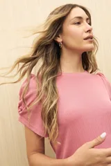 Top color rosado de tejido de punto acanalado, con mangas cortas abullonadas y cuello redondo.