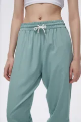 Pantalón de jogging color celeste con cintura elástica ajustable con cordón y puños elásticos. Presenta tres tiras verticales blancas en la parte inferior de la pierna.