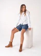 Bota corta de cuero color marrón claro, con cordones y detalles de perforaciones. Tiene un pequeño taco de madera.