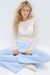 Pantalón de pijama celeste con rayas verticales blancas, de algodón suave, corte relajado, tiro bajo, cintura elástica, cierre decorativo con botones, piernas rectas y bolsillos laterales.