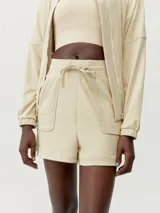 Short color beige con bolsillos frontales tipo parche, cintura con cordón ajustable y aberturas laterales.