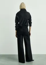 Pantalón de jean negro de corte wide leg, con tiro alto, bolsillos frontales de parche y cierre frontal con cremallera y botón.