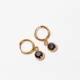 Aros dorados tipo argolla con dije circular colgante de piedra negra.