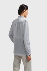 Camisa celeste claro con cuello mao y volados frontales, de corte holgado y manga larga.