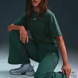 Pantalón deportivo Nike Sportswear Everything Wovens color verde con logo pequeño en blanco.