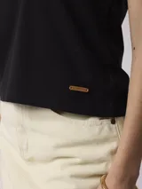 Remera negra sin mangas con cuello polo y tapeta con botones.