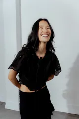 Blusa negra con bordado calado, escote en V con lazos para atar y mangas cortas abullonadas.