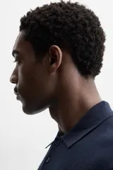 Polo de hombre color gris oscuro, de punto ligero tejido en hilatura con mezcla de seda y algodón. Tiene cuello solapa con cierre frontal de botonadura, manga larga y acabados en rib.