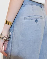 Pantalón gris de lino, de pierna ancha con pinzas, tiro medio, bolsillos laterales inclinados, raya de aplomo y bolsillos traseros ojal y con tapa. Tiene cierre y botón en la cartera y cintura interna prearmada.