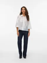 Camisa blanca traslúcida con bordado de flores blancas, de manga 3/4 con cuello camisero y calce regular. Con mangas amplias, puños anchos y cierre de botones.