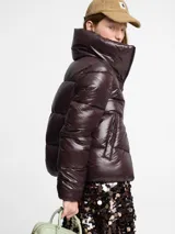 Chaqueta acolchada negra de nylon lacado, con cuello alto y cierre de cremallera bidireccional, diseñada sin materiales de origen animal.