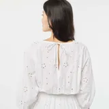 Vestido largo blanco con bordado inglés, escote en V, mangas 3/4 y corte en la cintura con abertura.