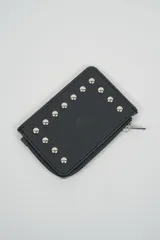 Billetera pequeña color negro con cierre de cremallera plateado y apliques de tachas metálicas redondas en la parte frontal.