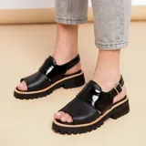 Sandalias negras de cuero vacuno con suela de goma deportiva, hebilla ajustable y horma ancha.