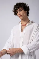 Camisa blanca de lino con cuello clásico, manga larga con puños abotonados y corte holgado. 