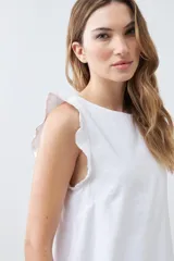 Vestido corto blanco de lino, sin mangas, con volados en los hombros y escote redondo.