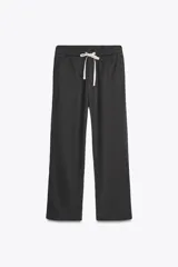 Pantalón de tiro medio con cintura elástica ajustable con cordones, bolsillos laterales ocultos en costura y pierna ancha. Confeccionado en hilatura con algodón y lyocell.