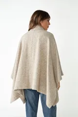 Capa con cuello, cierre frontal con botones y bolsillos delanteros. Confeccionada en lana fina sin teñir, diseñada exclusivamente por Don Baez.