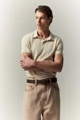 Remera polo de punto de algodón liviano color crema, de manga corta, corte ajustado y tapeta con botones.