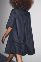Vestido corto de Zara Woman Collection confeccionado en tejido tipo denim. Tiene cuello solapa, manga corta, bolsillos delanteros ocultos, bajo evasé y cierre frontal con botones.