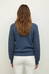 Sweater de punto acrílico color crema, con diseño de trenzas en el cuerpo y mangas, cuello redondo y calce holgado.