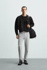 Pantalón largo de vestir gris claro con estampado de cuadros, corte slim fit y cintura elástica. Confeccionado en tejido con alta elasticidad, bolsillos frontales y cierre frontal con cremallera y botón.