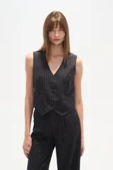 Chaleco de vestir sin mangas, color negro con finas rayas verticales blancas. Presenta escote en V, cierre frontal con botones y bolsillos falsos a la altura de la cintura.