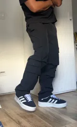 Pantalón cargo negro de corte recto con múltiples bolsillos con solapa y botón a presión.