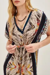Vestido midi estampado con cuello en V y mangas cortas. Presenta un diseño con cordón ajustable a la cintura y abertura frontal en la falda. El estampado es de estilo étnico o tribal en tonos beige, negro, amarillo y rojo.