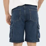 Bermuda de jean celeste lavado, estilo cargo, con bolsillos laterales con fuelle y cierre de botón y cremallera.