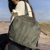 Mochila color topo agamuzada con detalle tramado al frente, apertura superior con cierre metálico, división al medio y bolsillos internos. Incluye correa corta de mano y correas regulables para colgar en la espalda.