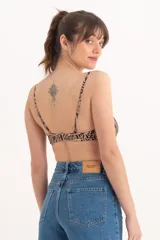Top de bikini con estampado animal print en tonos beige y negro, con breteles finos y diseño cruzado en el centro del busto.
