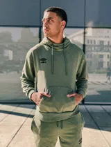 Canguro de felpa verde militar con capucha y cordones, bolsillo tipo canguro y logo Umbro bordado en el pecho.