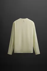 Camiseta deportiva de manga larga color amarillo pálido, confeccionada en tejido técnico perforado, ligero y elástico.