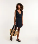 Vestido corto de playa color negro, confeccionado en crepé, con escote delantero y trasero, fruncido con lazo en los hombros y sin estampa.