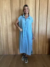 Túnica celeste de corte recto, con cuello camisero, mangas cortas, tajos laterales y cierre frontal con botones.