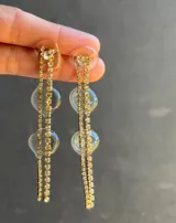 Par de aros largos con base de resina transparente y tiras de strass doradas.