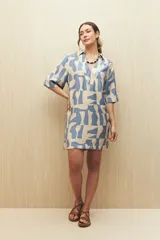 Vestido corto con estampado geométrico en tonos beige y celeste, cuello tipo solapa y escote en V, mangas 3/4 y silueta amplia.